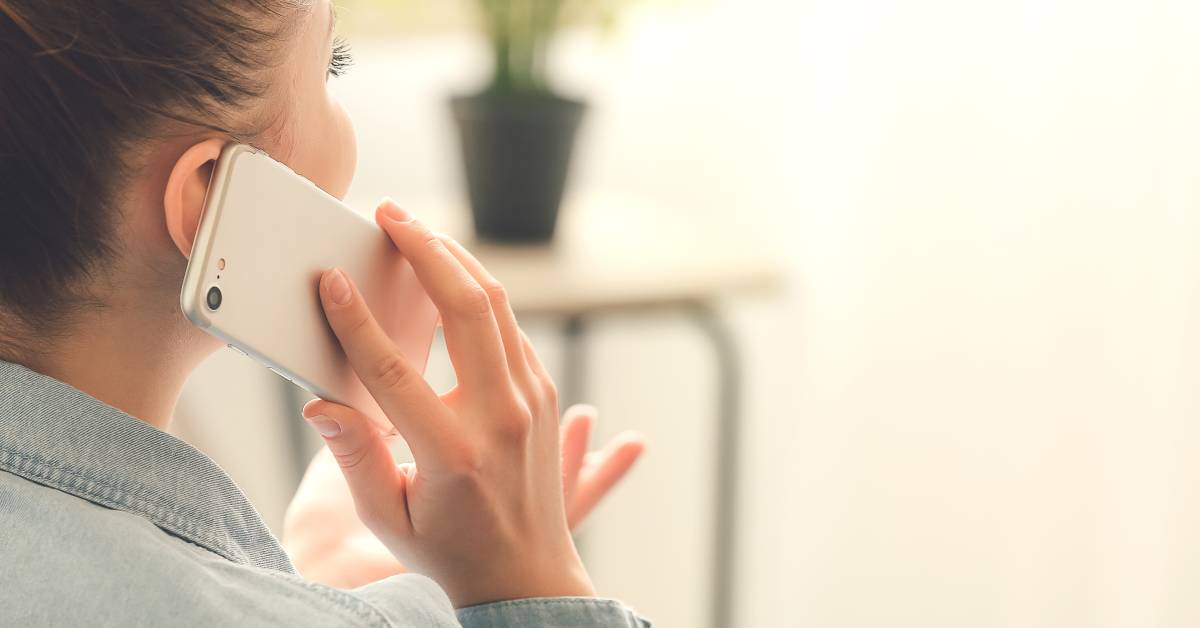 A person in a faded blue jacket is gesturing with their free hand while talking on a cell phone with the other hand.