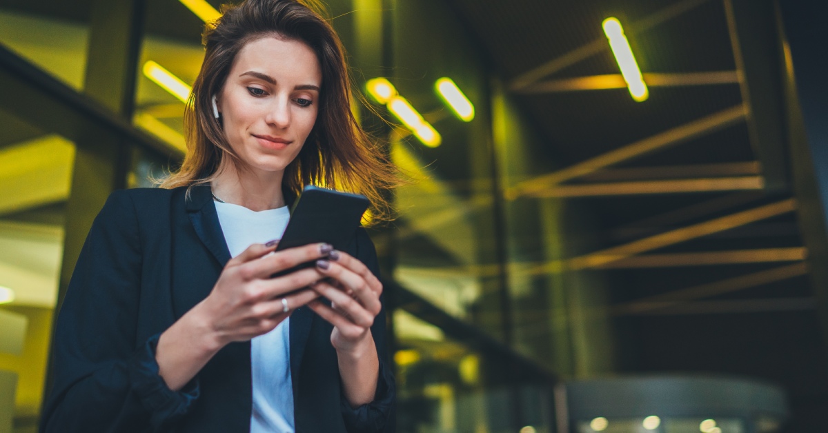 A professional wearing a business suit is smiling while using their phone in a high-end business space.