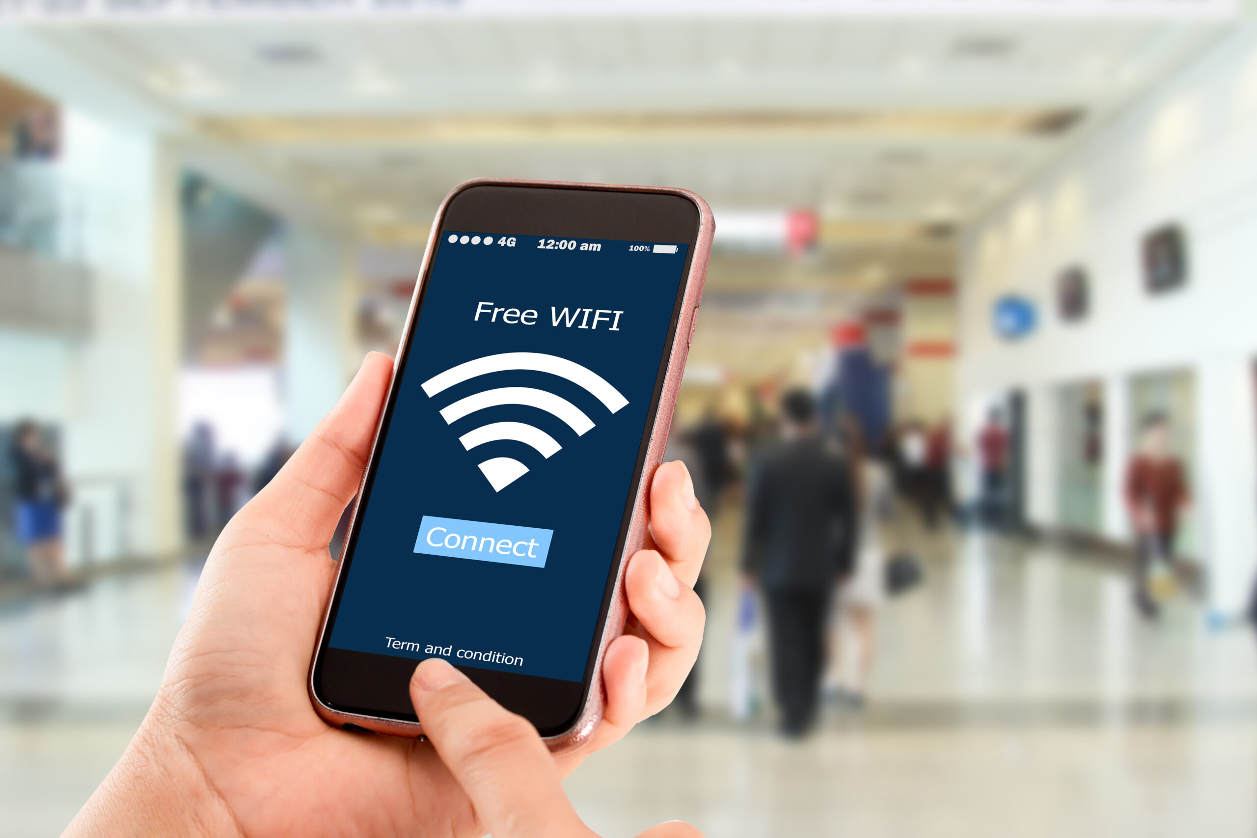 A person holding their phone in a public place. A “Connect” prompt is on the phone screen under a “Free WIFI” banner.